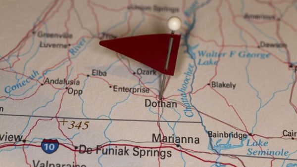 A map pin with a red flag pinpoints the city on a select area from a high quality map. The red flag creates highlighted copy space for text.
