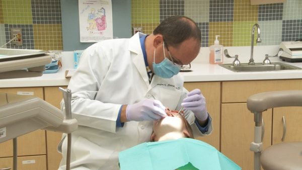 Close-up of Dr. Stephen Mitchell (Pediatric Dentistry) performing dental exam on unidentified patient.